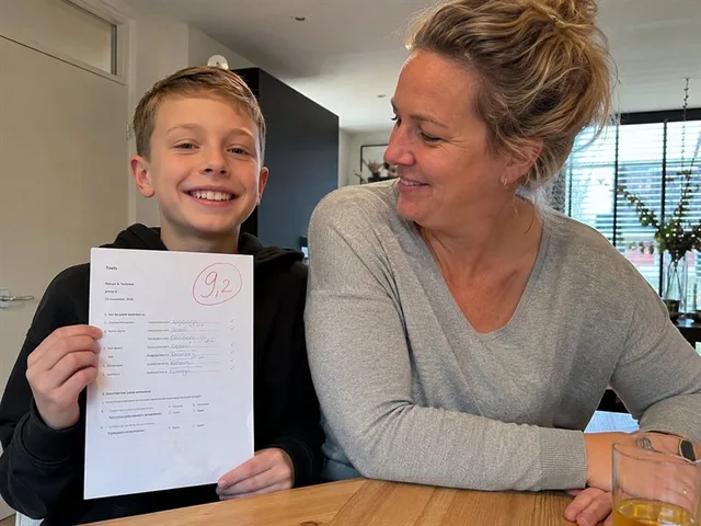 Foto: een leerling laat trots een proefwerk met een 9,2 zien.
